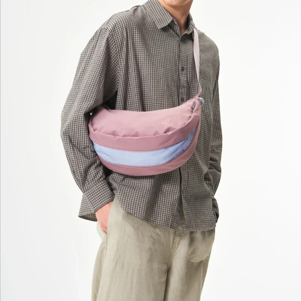 Lieblingstasche sling bag in dusty rose and light blue worn crossbody by a man in a plaid shirt and beige cap