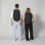 Lieblingstasche Easy27 black everyday backpack worn by a man and woman, showing back view and padded shoulder straps.