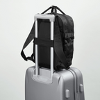 Lieblingstasche eoto Small16 black daypack attached to a silver suitcase handle for travel