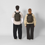 Lieblingstasche eoto Small16 compact daypack in dark brown worn by a man and a woman against a light grey background