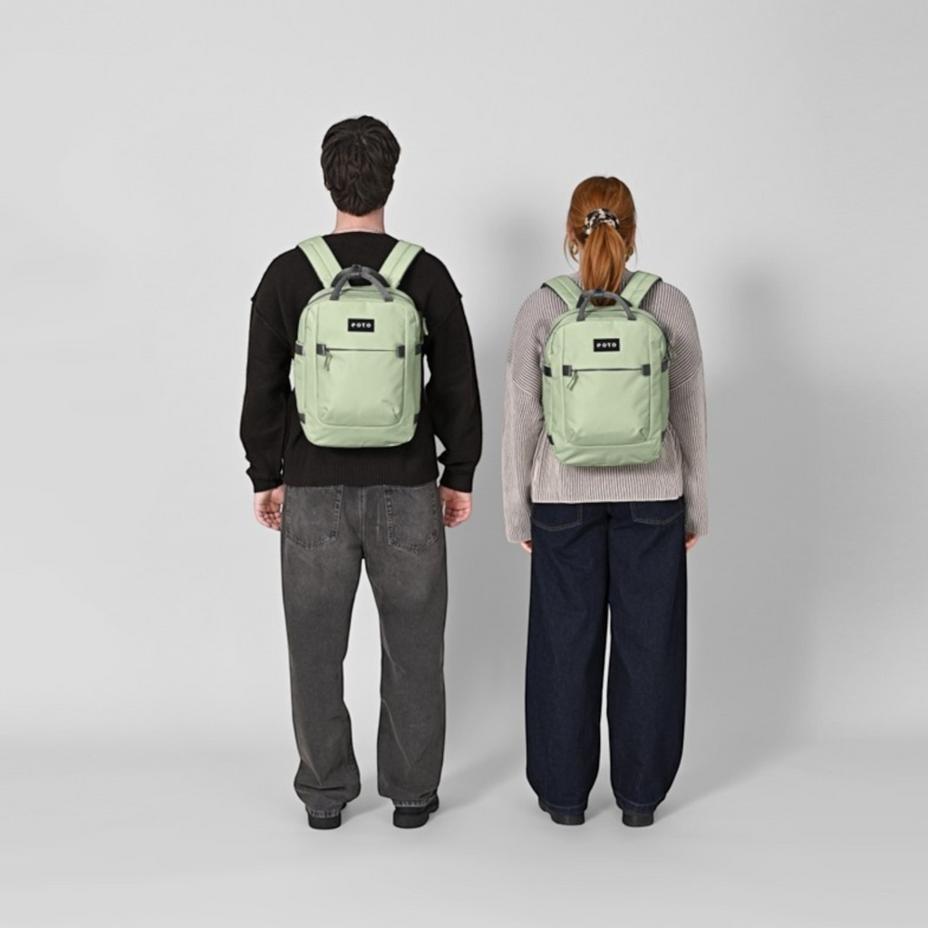 Lieblingstasche eoto Small16 compact sage green daypack worn by a man and woman against a neutral background