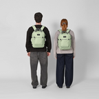 Lieblingstasche eoto Small16 compact sage green daypack worn by a man and woman against a neutral background