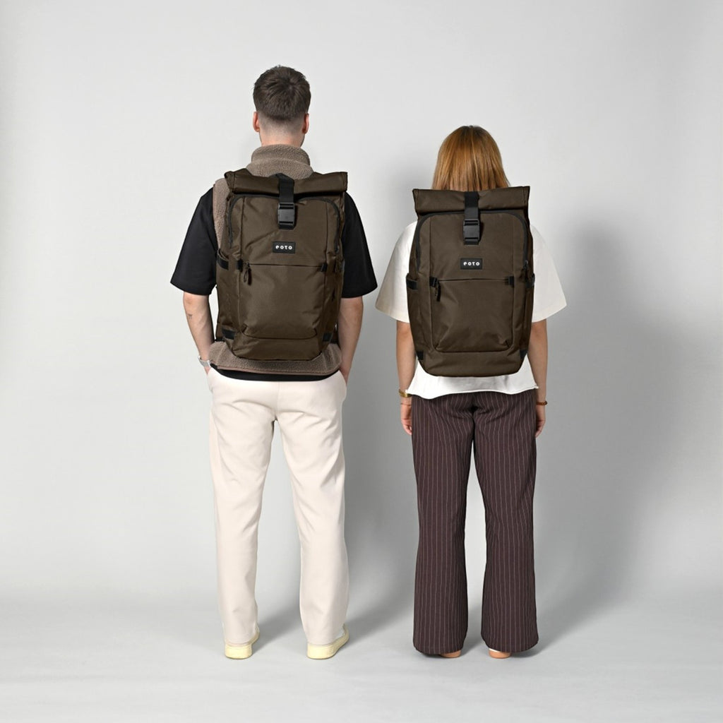 Lieblingstasche eoto Tall41 brown rolltop travel backpack worn by a man and woman against a light grey background