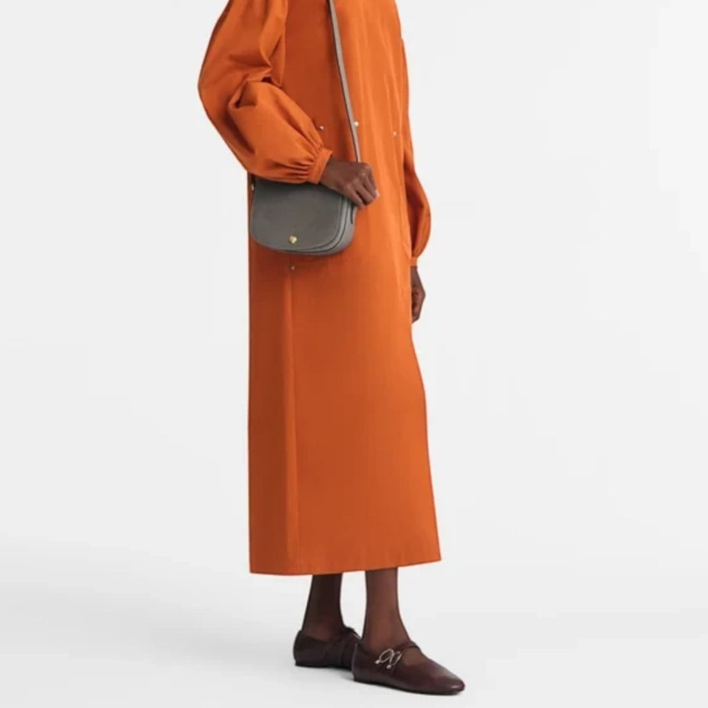 Lieblingstasche Epure S crossbody bag in grey worn by a model in an orange dress