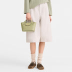 Lieblingstasche Epure Umhängetasche XS, a small light green leather handbag with a top handle and a gold clasp.