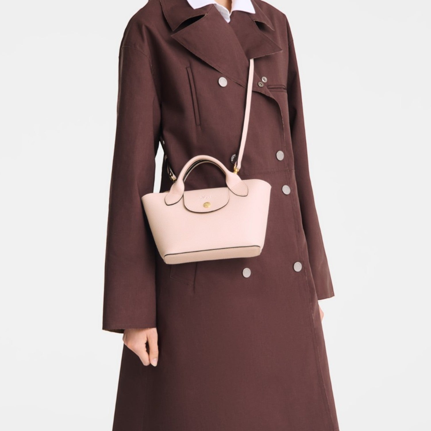 Lieblingstasche Epure XS light pink leather handbag with top handle and crossbody strap worn by a model.
