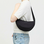 Lieblingstasche Essential Moon Bag in black worn as a shoulder bag by a woman in a white top and jeans