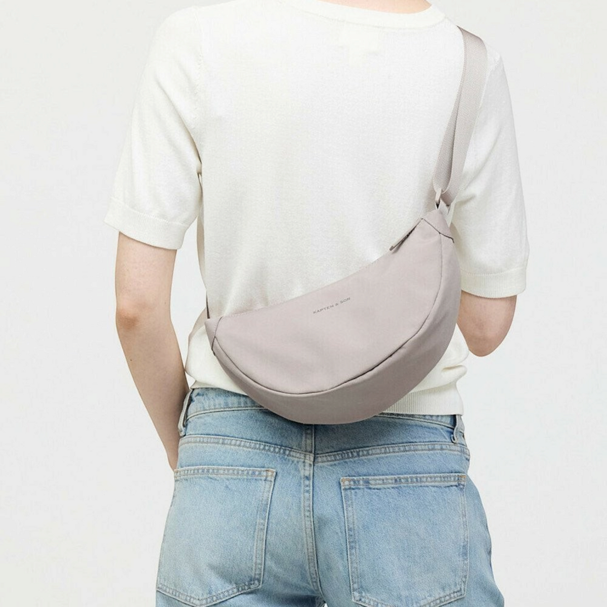 Lieblingstasche Essential Moon Bag in light grey worn as a crossbody bag by a woman in a white top and jeans