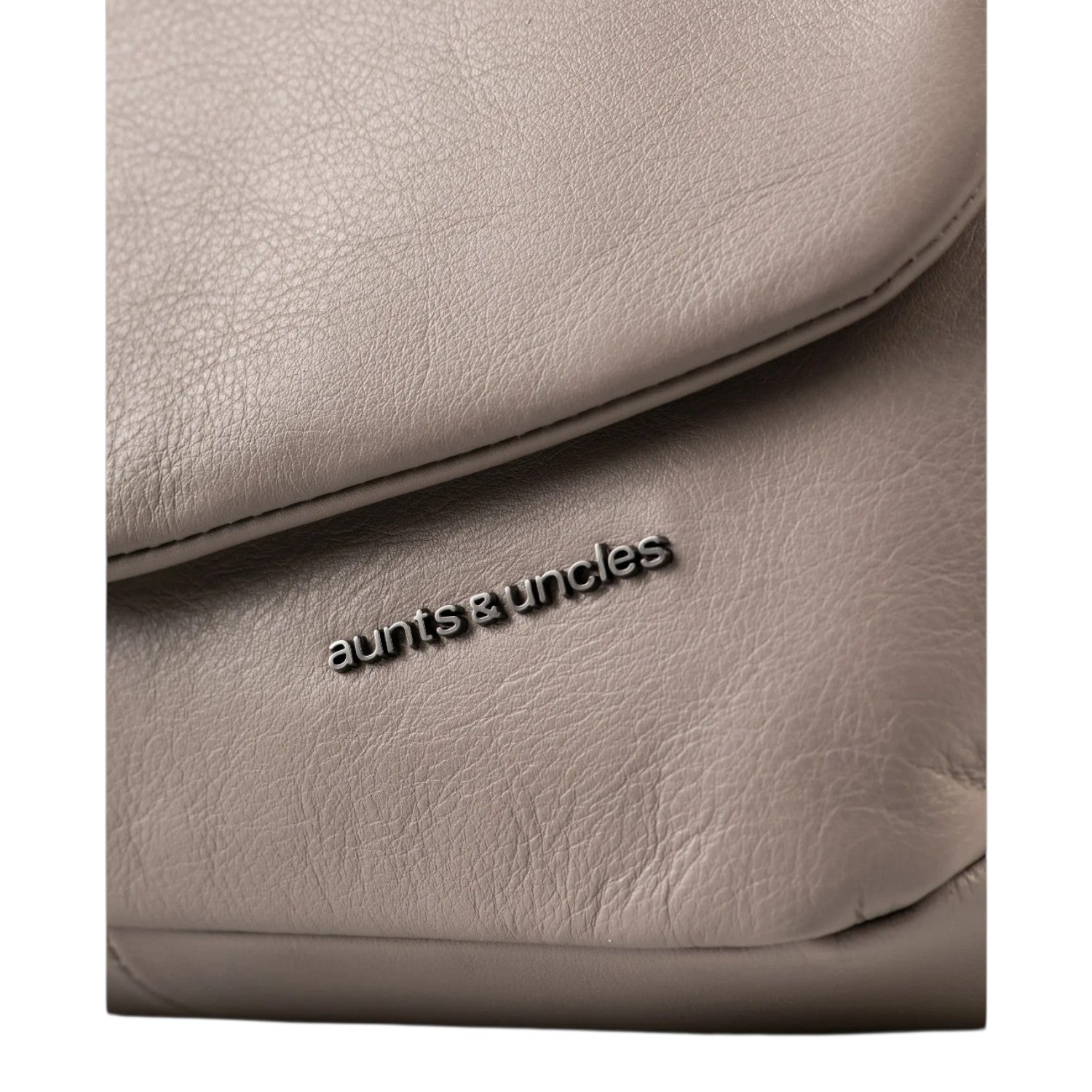 Close-up of a taupe leather Fern bag by Lieblingstasche featuring the aunts & uncles metal logo plate.
