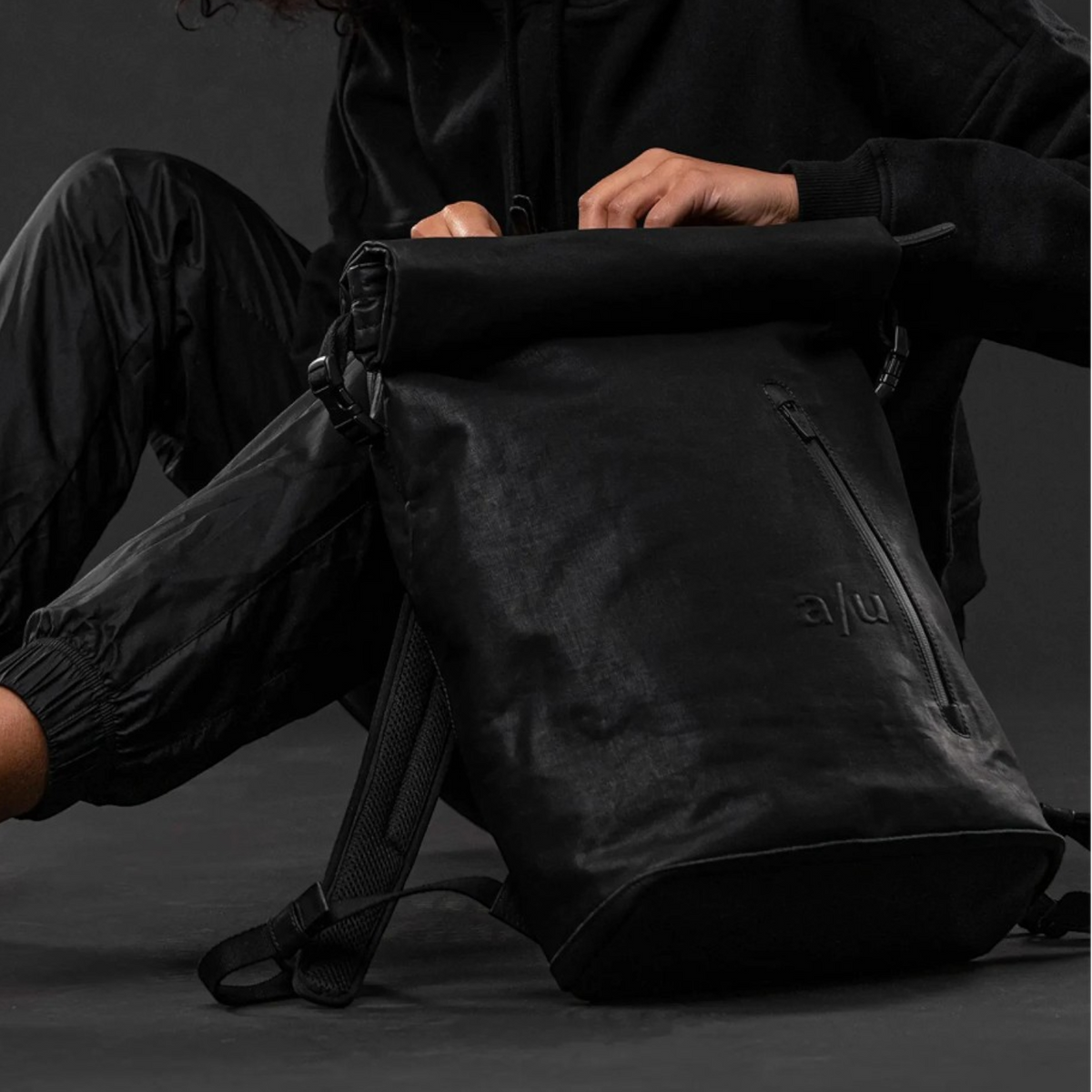 Lieblingstasche a/u by aunts & uncles Fukui black rolltop backpack with leather details worn by a smiling woman