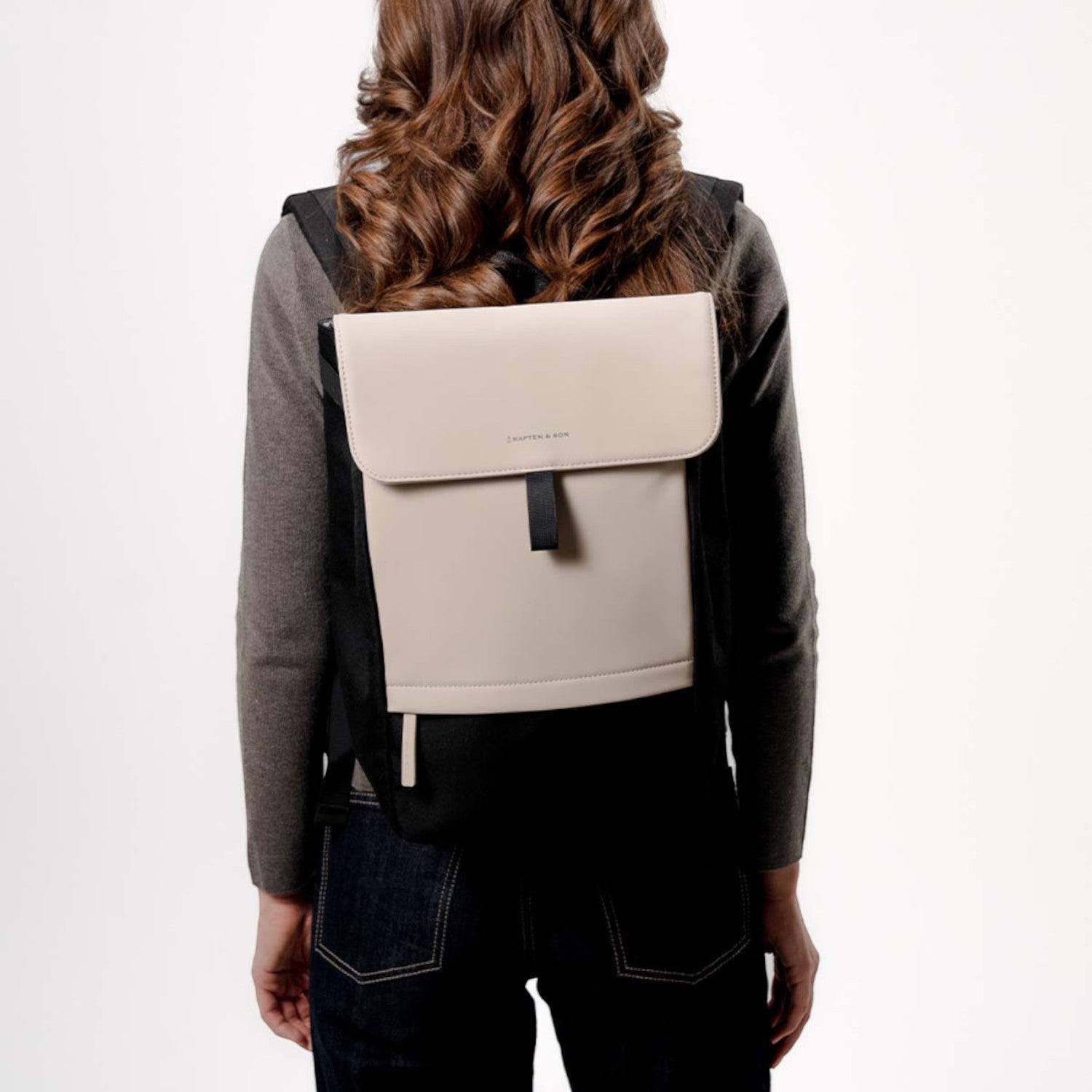Lieblingstasche Kapten & Son Fyn backpack in beige and black with a minimalist flap design worn by a woman