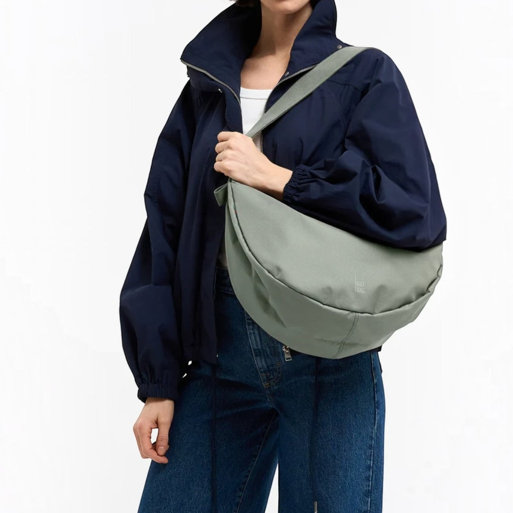 Lieblingstasche GOT BAG Moon Bag Large in sage green worn crossbody by a woman in a navy jacket