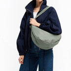 Lieblingstasche GOT BAG Moon Bag Large in sage green worn crossbody by a woman in a navy jacket