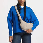 Lieblingstasche GOT BAG Pleat Moon Bag Small in beige, worn as a crossbody bag by a model in a blue sweater.