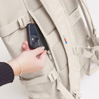 Lieblingstasche GOT BAG Rolltop 2.0 backpack in beige showing a hand placing a smartphone into a side zipper pocket
