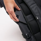 Lieblingstasche GOT BAG Rolltop 2.0 black backpack showing a hand placing a smartphone into a side zipper pocket