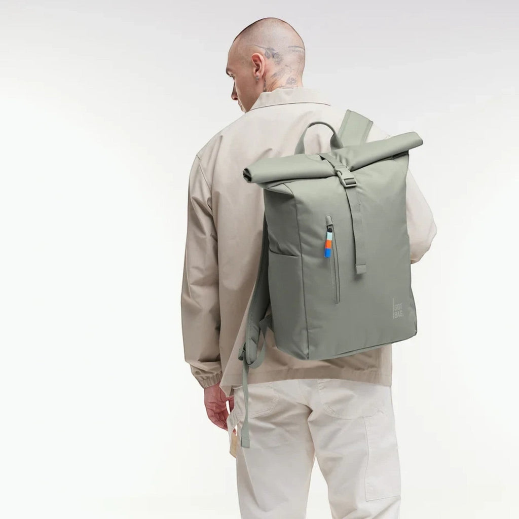 Lieblingstasche GOT BAG Rolltop Easy backpack in sage green, worn by a man in a beige jacket against a white background