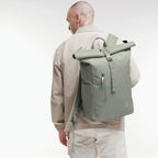 Lieblingstasche GOT BAG Rolltop Easy backpack in sage green, worn by a man in a beige jacket against a white background