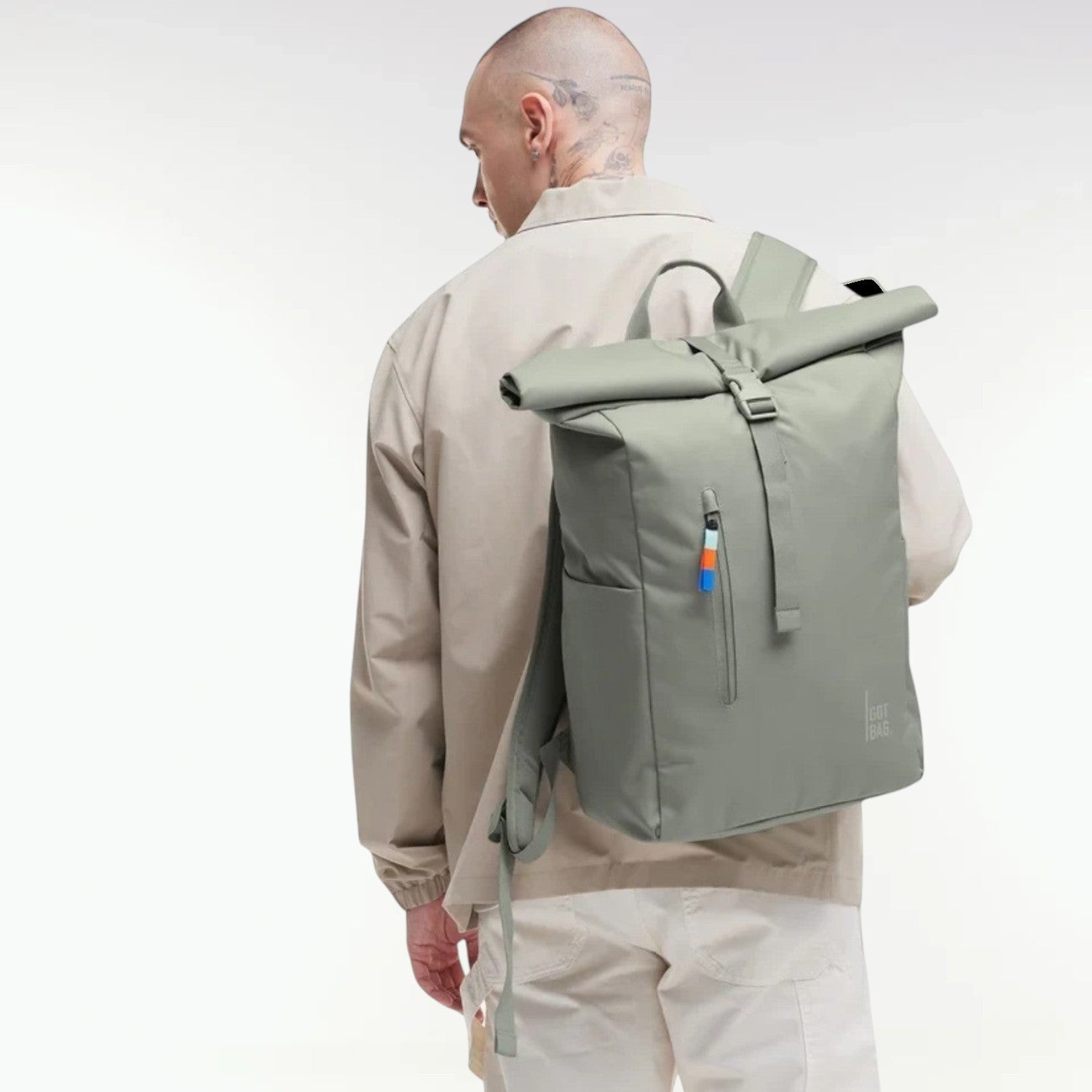 Lieblingstasche GOT BAG Rolltop Easy backpack in sage green, worn by a man in a beige jacket against a white background