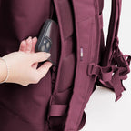 Lieblingstasche GOT BAG Rolltop Lite 2.0 backpack in burgundy with a hand placing a smartphone into a side pocket.