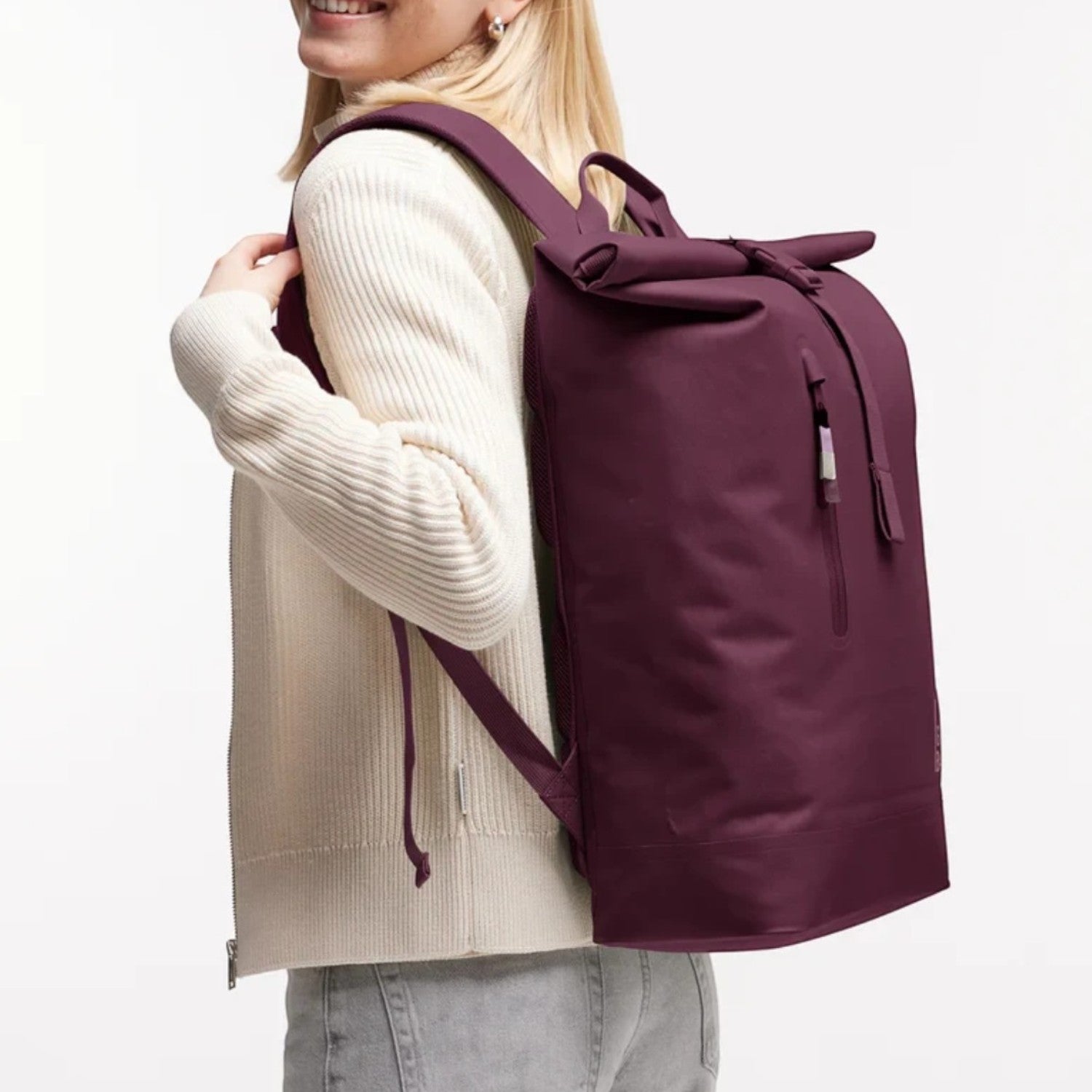 Woman wearing a dark purple GOT BAG Rolltop Lite 2.0 backpack from Lieblingstasche, featuring a sleek, modern design.