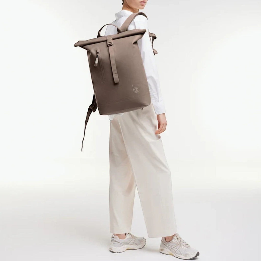 Lieblingstasche GOT BAG Rolltop Lite 2.0 backpack in taupe worn by a model in a white shirt and trousers