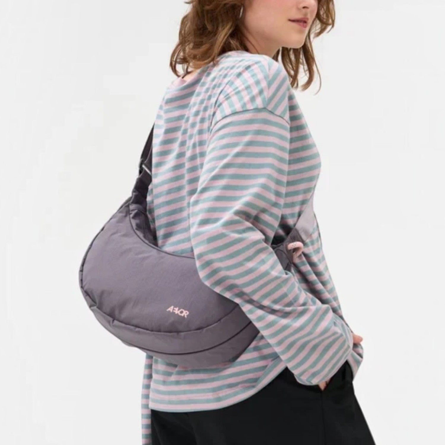 Woman wearing a grey Lieblingstasche sling bag crossbody, featuring a minimalist design and water-resistant material.