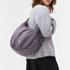 Lieblingstasche slouchy bag in grey worn over the shoulder by a woman in a striped long-sleeve shirt