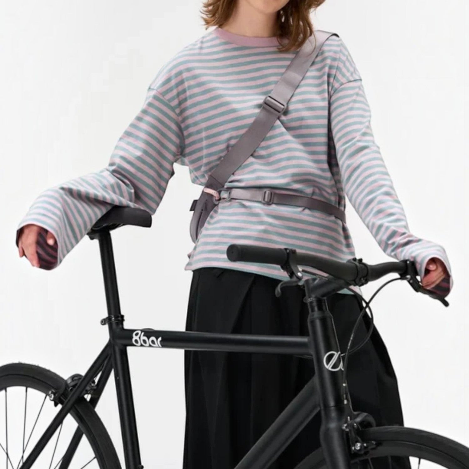 Lieblingstasche grey water-resistant sling bag worn crossbody by a woman standing with a bicycle.