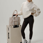 Lieblingstasche Hellvi Cloud Medium beige padded bag on a matching suitcase with a model in casual sportswear