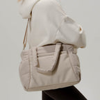 Lieblingstasche Hellvi Cloud Medium beige padded shoulder bag with laptop compartment worn by a woman