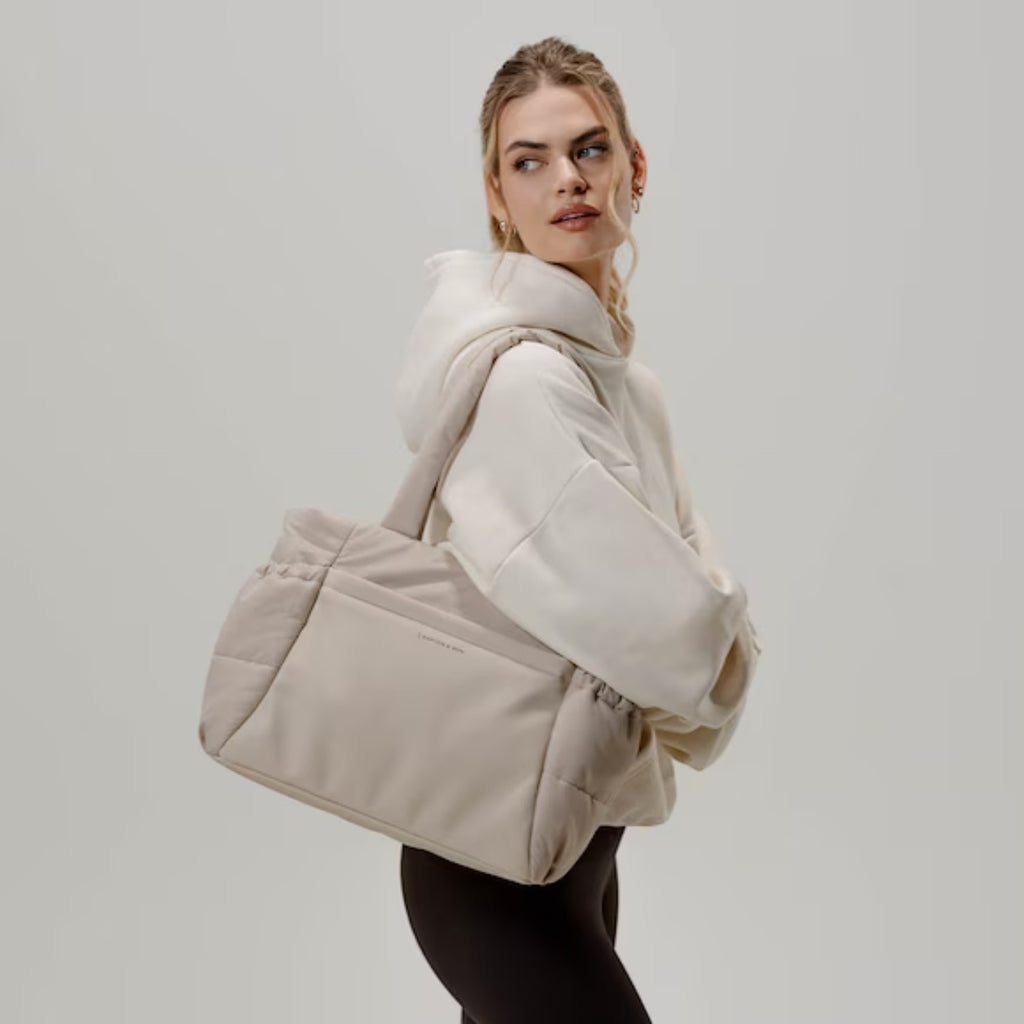 Lieblingstasche Hellvi Cloud Medium beige quilted tote bag with laptop compartment worn by a woman in a hoodie
