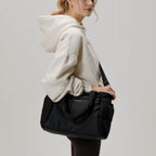 Lieblingstasche Hellvi Cloud Medium black padded shoulder bag with laptop compartment worn by a woman