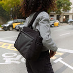 Lieblingstasche Hellvi Cloud Medium black padded shoulder bag with side bottle pockets worn by a woman in the city