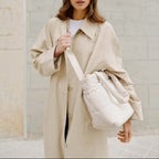 Lieblingstasche Hellvi Cloud Medium bag in cream with padded design worn by a woman in a beige trench coat