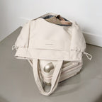 Lieblingstasche Hellvi Pro Large beige travel tote bag with drawstring sides resting on a matching suitcase
