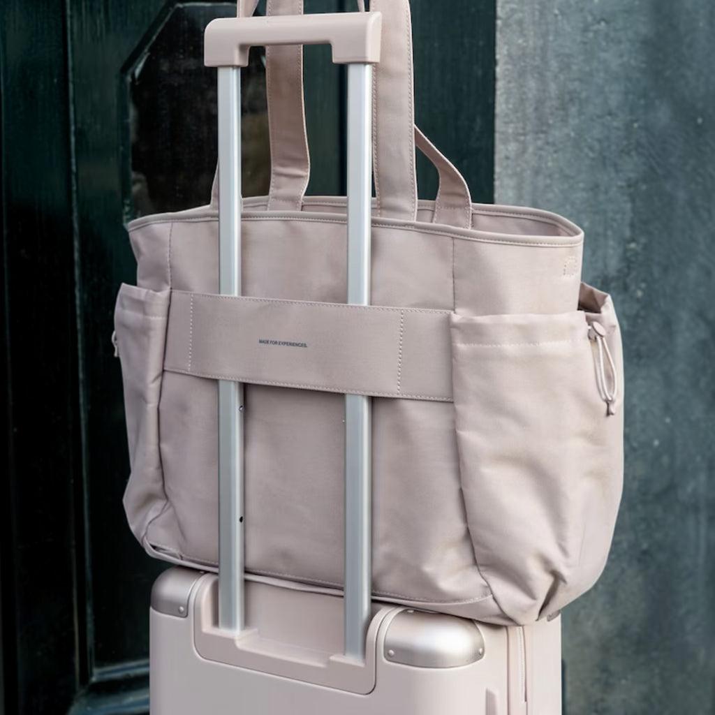 Lieblingstasche Hellvi Pro Large beige travel tote bag with luggage sleeve attached to a matching suitcase handle.