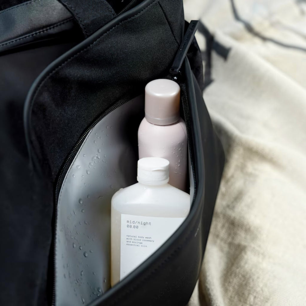 Lieblingstasche Hellvi Pro Large black bag with a zippered side pocket containing a bottle of body wash and spray