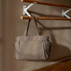 Lieblingstasche Hellvi Pro Large tote bag in taupe with side pockets hanging on a wooden rack