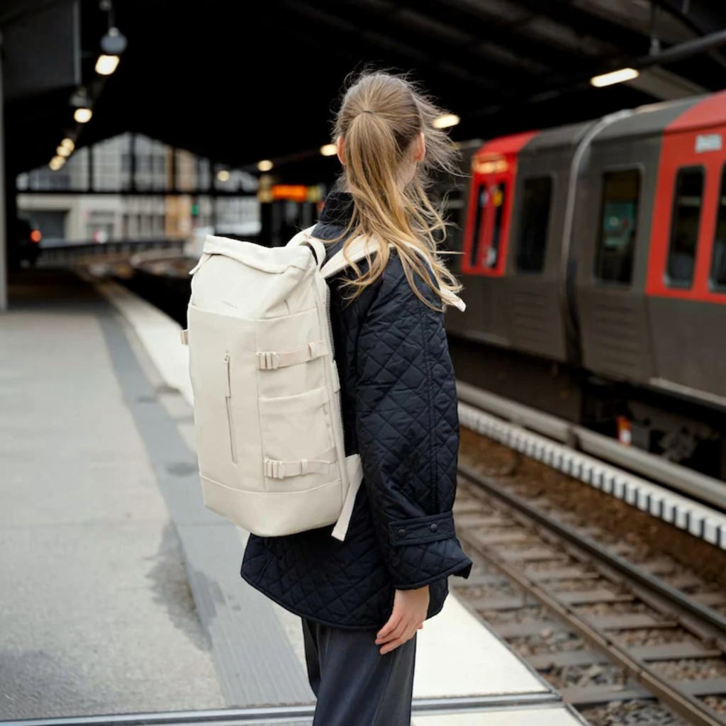 Lieblingstasche Helsinki Pro beige rolltop backpack worn by a woman on a train platform