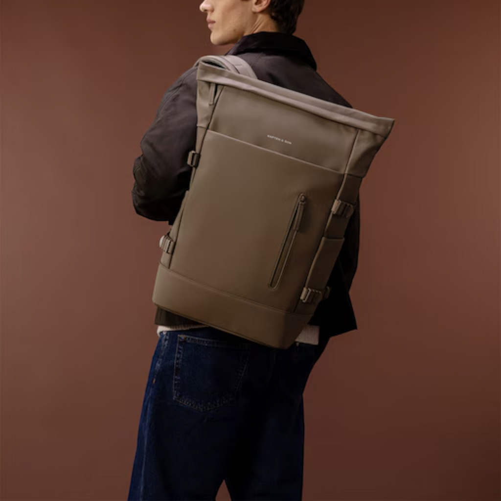 Lieblingstasche Helsinki Pro backpack in taupe worn by a man in a dark jacket against a brown background