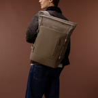Lieblingstasche Helsinki Pro backpack in taupe worn by a man in a dark jacket against a brown background