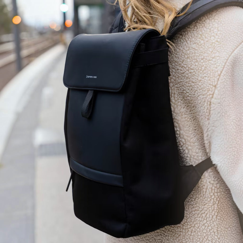 Lieblingstasche Kapten & Son Fyn minimalist black backpack with padded straps worn by a person in a fleece jacket
