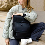 Lieblingstasche Kapten & Son Fyn minimalist black backpack worn by a woman in a sage green jacket outdoors