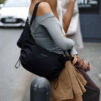 Lieblingstasche Kapten & Son Skara Small black crossbody bag worn by a woman in a grey top and brown skirt
