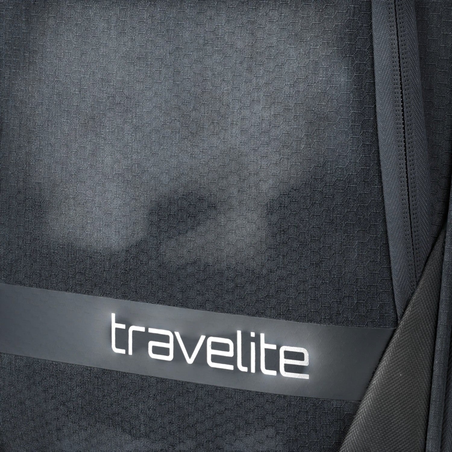 Close-up of the dark grey textured fabric on a Lieblingstasche KICK OFF trolley suitcase with travelite branding.