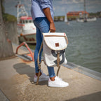 Lieblingstasche Landgang Mini backpack in white canvas with grey accents, held by a person at a harbor.