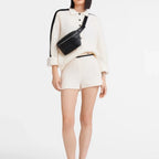 Lieblingstasche Le Foulonné black leather belt bag worn as a crossbody by a model in a cream knit set