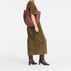 Lieblingstasche Le Foulonné XL shoulder bag in dark burgundy leather worn by a model in an olive green dress