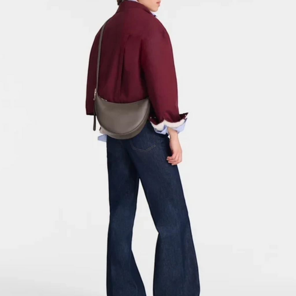 Lieblingstasche Le Foulonné Umhängetasche S in grey leather worn as a crossbody bag by a model in a burgundy jacket